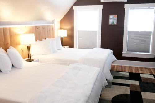 two white beds in a room with two windows at Inn at Kampfires in Dummerston Center