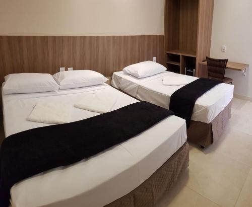 a hotel room with two beds in a room at Bravo City Hotel Campo Grande in Campo Grande
