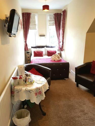 a small room with a bed and a table with a table at The Palms Guest house in Torquay