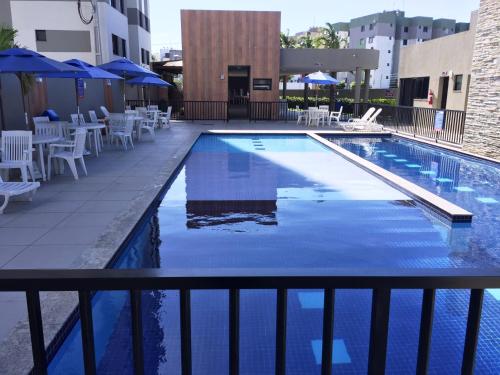 una gran piscina con sillas y sombrillas blancas en Apto próximo à Fac. Pio X, en Aracaju