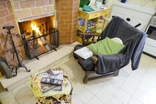 a living room with a fireplace and a chair and a table at La casa di Zia Mimina in Civitella Casanova