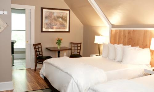 a hotel room with a large white bed and a table at Inn at Kampfires in Dummerston Center