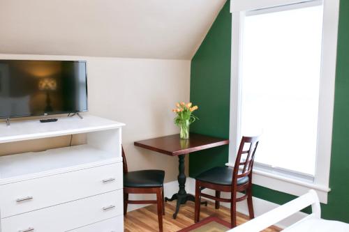 a room with a table and chairs and a tv at Inn at Kampfires in Dummerston Center