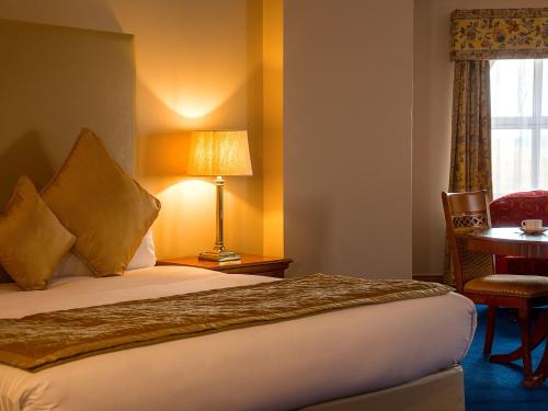 a hotel room with a bed and a table and a window at Lady Gregory Hotel, Leisure Club & Beauty Rooms in Gort