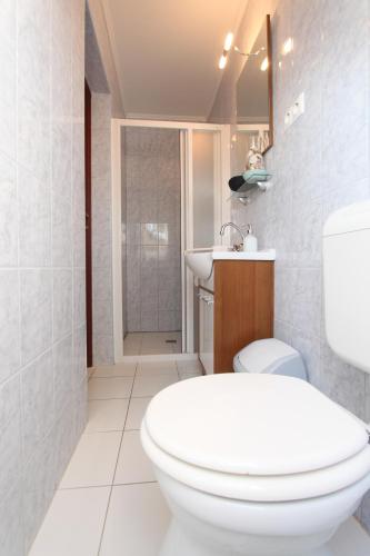 a white bathroom with a toilet and a sink at Sorompó Vendégház in Balatonkenese