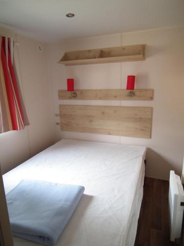 Cette petite chambre comprend un lit blanc et des étagères en bois. dans l'établissement Camping La Pindière, à Héric