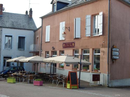 a restaurant with tables and umbrellas in front of a building at Le Lion D'or in Ouroux en Morvan