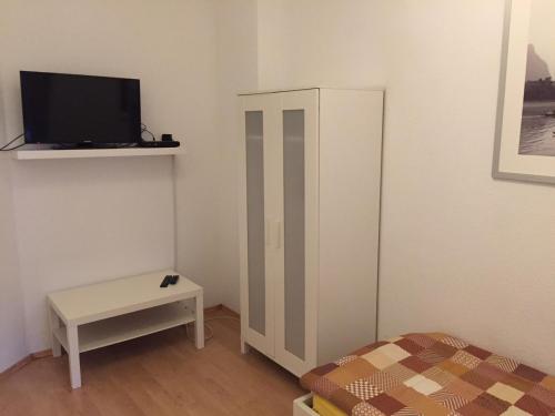 um pequeno quarto com uma cama e uma televisão na parede em Hannover Südstadt - Zimmer und Apartment em Hanôver