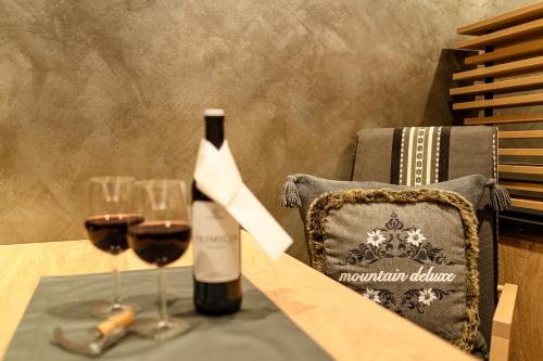 a bottle of wine and two glasses on a table at "Haus Berktold" - Annehmlichkeiten von 4-Sterne Familien-und Wellnesshotel Viktoria können mitbenutzt werden in Oberstdorf