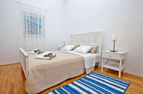 ein weißes Schlafzimmer mit einem Bett und einem blauen Teppich in der Unterkunft Apartments Roses Stobrec in Split