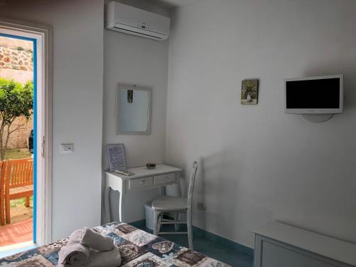 a bedroom with a bed and a desk and a television at La Casa del Limoneto in Favignana