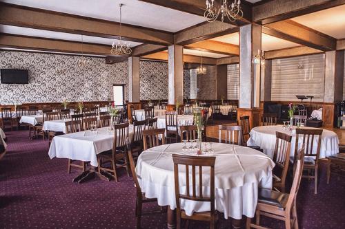 Hanul Ursilor في تارجو نيمت: غرفة طعام مع طاولات وكراسي بيضاء