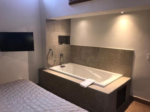 a bathroom with a bath tub next to a bed at Hotel Grand Maria in San Cristóbal de Las Casas
