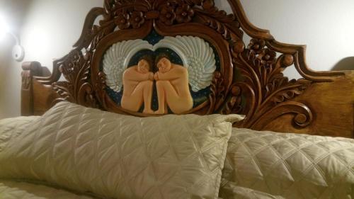 a bed with a wooden head board with two angels at Hotel Grand Maria in San Cristóbal de Las Casas