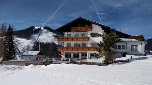a large building in the snow in front of a mountain at Der Brückenhof Ramsau in Ramsau am Dachstein