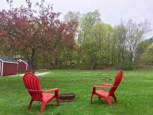 two red chairs sitting in the grass in a yard at Inn at Kampfires in Dummerston Center