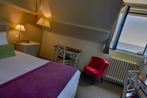 a bedroom with a bed and a red chair and a window at Le Grand Large, Belle-Ile-En-Mer in Bangor