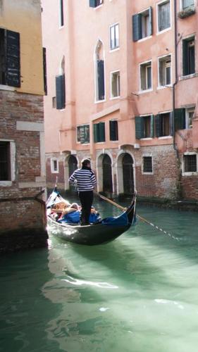 a man is standing on a gondola in a canal at Casa Marco Polo in Venice