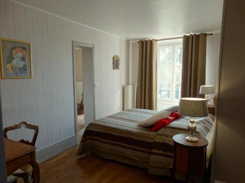 a bedroom with a bed with a lamp and a window at B&B Girolles les Forges in Girolles