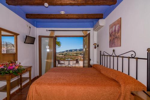 1 dormitorio con 1 cama y balcón con vistas. en Hotel Rural Almazara, en Frigiliana