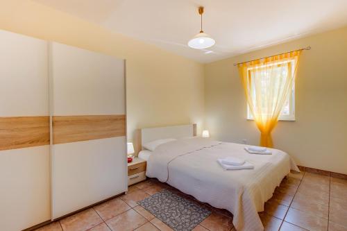 a bedroom with a white bed and a window at Apartmani Villa Casper in Veli Lošinj