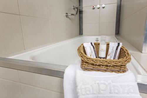 El baño incluye una cesta de toallas junto a la bañera. en Crystal Plaza Hotel, en Goiânia