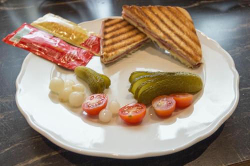 a plate with a sandwich and pickles and tomatoes at Ferienhof Alte Post, Apartments in Weissbriach