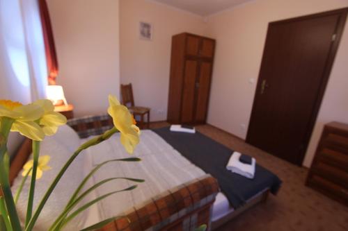 a room with a bed and a vase with yellow flowers at Sorompó Vendégház in Balatonkenese