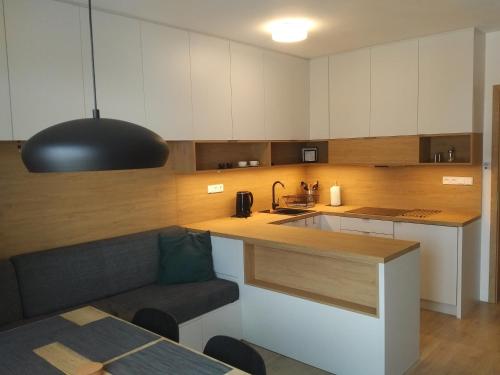 une cuisine avec des placards blancs et une lampe pendant noire dans l'établissement Apartmány Sport Dolní Morava, à Dolní Morava