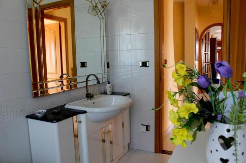 a bathroom with a sink and a vase with purple flowers at La casa di Bia in Corleone