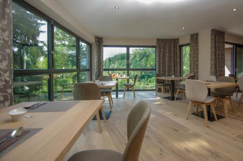 a dining room with tables and chairs and large windows at Apartment Hotel Christine in Avelengo