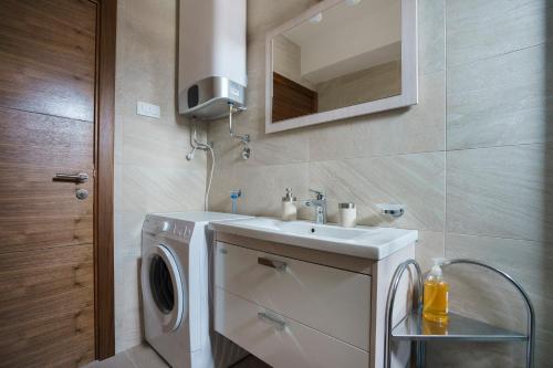 uma casa de banho com uma máquina de lavar roupa e um lavatório em Apartments LORA Jadranskij put em Budva
