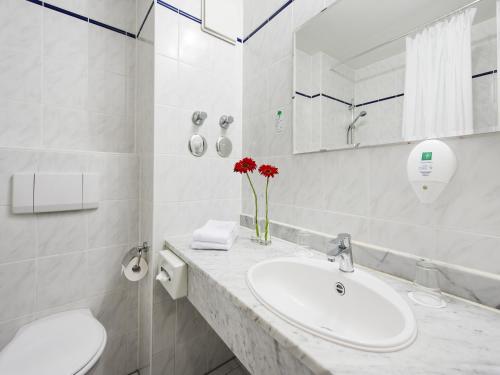 a white bathroom with a sink and a mirror at Andante Hotel Erding in Erding