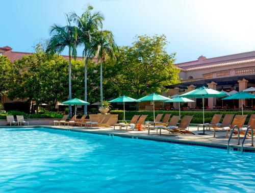 a pool with chairs and umbrellas in it at The Langham Huntington, Pasadena in Pasadena
