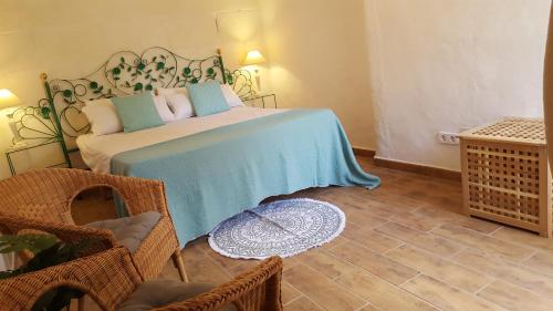 a bedroom with a bed with a blue blanket and chairs at Habitaciones Casa de Campo Daymipaz in Mahón