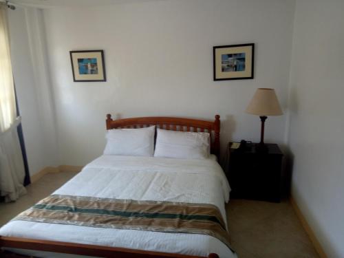 a bedroom with a bed with white sheets and a lamp at Metro Vigan Inn in Vigan