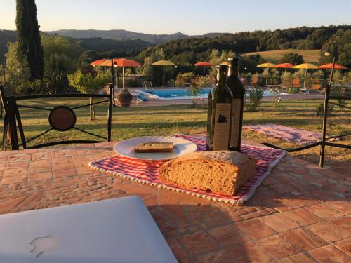 uma garrafa de vinho e um pão sobre uma mesa em Farmhouse Gello by ToscanaTour em Montecatini Val di Cecina