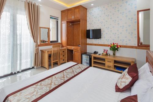 een slaapkamer met een bed, een bureau en een televisie bij Nhat Minh Anh Hotel in Ho Chi Minh-stad