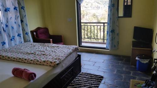 a bedroom with a bed and a window and a chair at Hotel Sanskaar in Bandipur
