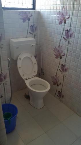 a bathroom with a toilet with purple flowers on the wall at Hotel Sanskaar in Bandipur