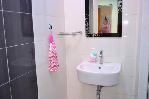 een witte badkamer met een wastafel en een spiegel bij branded hotel in Melaka