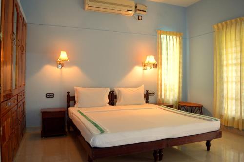 una camera da letto con un grande letto con lenzuola bianche di Ganesh Ayurveda Holiday Home Apartment a Kovalam