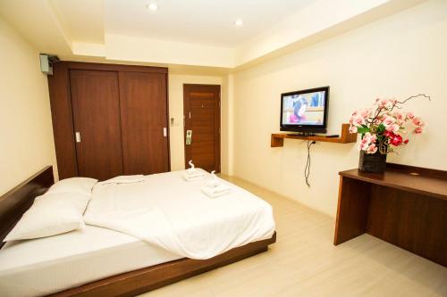 a bedroom with a bed and a tv on a wall at The Loft Resort Bangkok in Bangkok