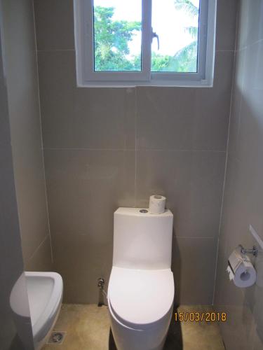 a bathroom with a white toilet and a window at Cabilao Sunset Dive & Beach Resort in Loon
