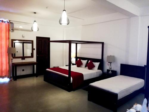 a bedroom with two beds with red and white pillows at Hasara Hotel Galle in Galle