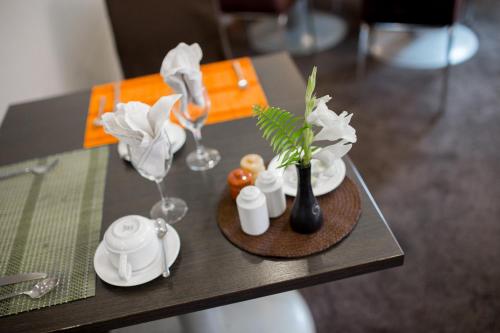 a table with two wine glasses and a vase with flowers at TANA Hotel in Antananarivo