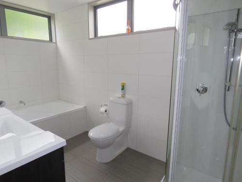 een witte badkamer met een toilet en een douche bij The Links Carters Beach Apartments in Carters Beach