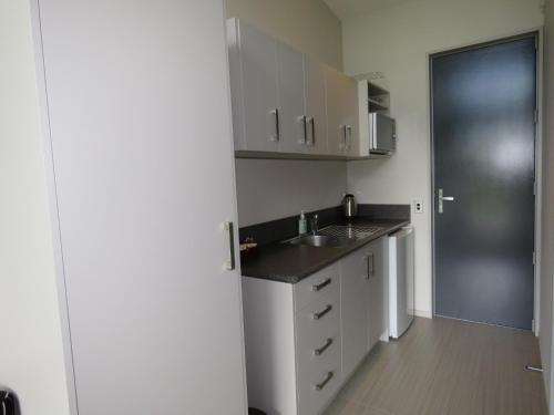 a kitchen with white cabinets and a sink and a door at The Links Carters Beach Apartments in Carters Beach