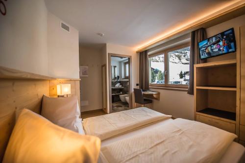 a bedroom with a bed and a desk and a window at Hotel Le Alpi in Livigno