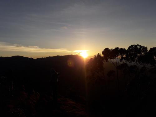 una persona in piedi su una collina al tramonto di Ella Infinity View a Ella